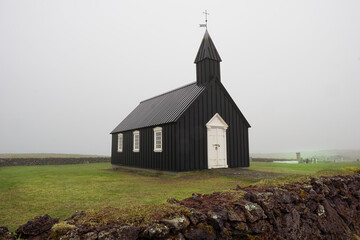 Veiled in fog, Iceland's black church stands as a solemn sentinel, echoing mysteries of ages past.