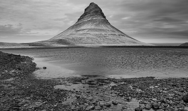 Kirkjufell's shadowed reflection, a monochrome memory where land, water, and clouds entwine.
