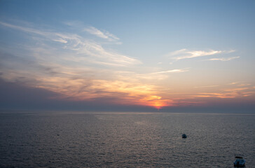 Sun halfway set on the horizon on a cape cod bay beach