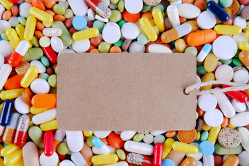 A lot of scattered multicolored pills, capsules with an empty price tag for the text.Production and disposal of medicines.Pharmaceutical preparations.Sale of medicines.Vitamins for a healthy lifestyle