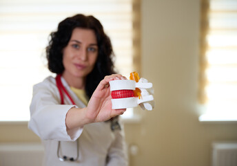 Portrait of young female neurologist or professor showing spine anatomy to patients or students....