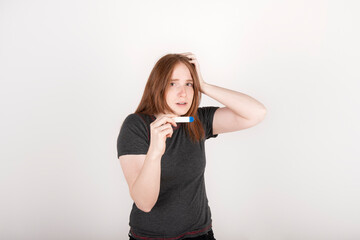 Fototapeta premium Shocked red haired woman clutching her head when she finds out about her pregnancy. Worried expression. White bacground