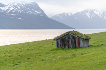 Small hut by the fjord's shore line. Old fishing huts making the scenery even nicer. Massive snowy...