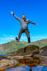 Obraz premium Man adventurer Norway Travel hiking lifestyle concept active weekend summer vacations. Life on the edge Traveler on cliff mountains over fjord enjoying Norway landscape. active healthy lifestyle