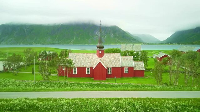 Scenic old red church in Flakstad on Lofoten Islands.  Traditional village in Norway. Summer arctic landscape, tourism destination. 