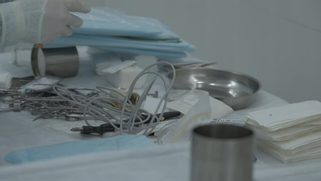 A table of medical tools are placed upon a table in preparation for surgery. Stock footage. Nurse putting instruments on the table.