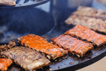 BBQ cook grills pork ribs on open fire. Turns meat over with tongs. Concept Street food