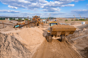 Aerial top view mining excavator loading sand in lorry truck in opencast. Open pit mine concept