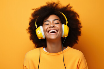 Smiling african american woman listen to music on headphones on orange background - obrazy, fototapety, plakaty