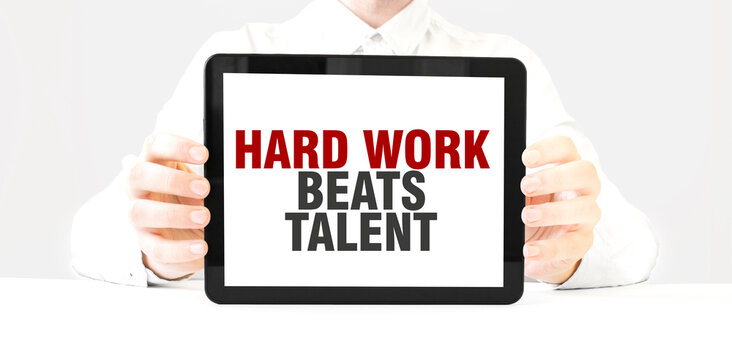 Text HARD WORK BEATS TALENT on tablet display in businessman hands on the white background. Business concept