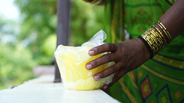 a women crushing jaggery by hand manually in indian village stock footage