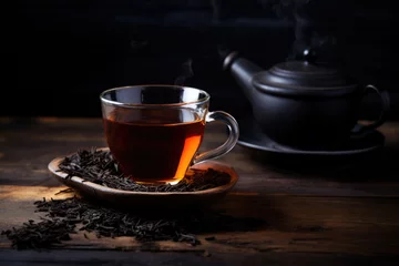 Poster Fresh hot black tea in a cup on a dark rustic background © pilipphoto