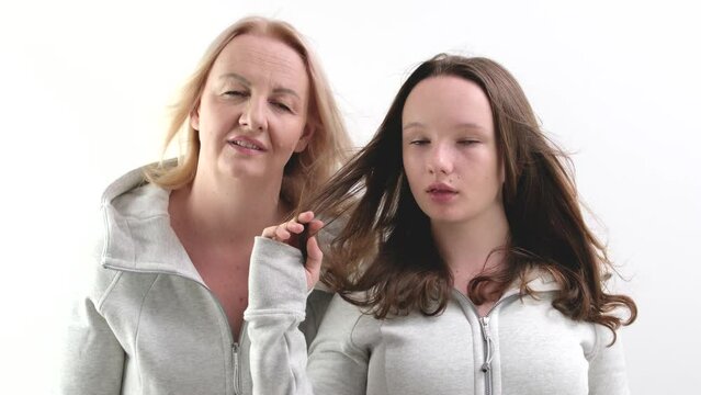 close-up faces of European women, an adult and a young girl looking into the frame, mother and daughter pointing with a finger, breaking hair. white background