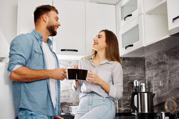 Young happy couple drinking first morning coffee in kitchen