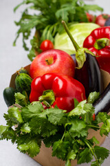 Craft baskets with fresh vegetables, fruits and herbs on a light background, close up.