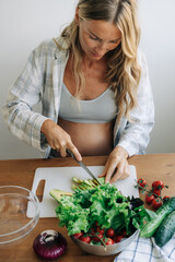 Beautiful young pregnant woman chop vegetables to prepare a salad.