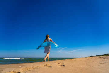 Fototapeta na wymiar Happy beautiful woman walking on sunny beach 