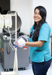 Young and pretty latin-looking laboratory and blood bank technician performing whole blood...