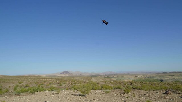 Man using jet pack flies high over desert