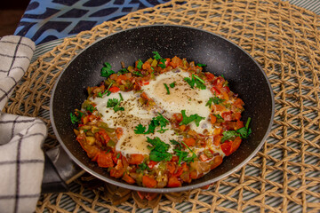 Shakshouka is a Maghrebi dish of eggs poached in a sauce of tomatoes, olive oil, peppers, onion, and garlic, commonly spiced with cumin, paprika and cayenne pepper.