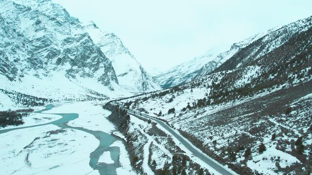4k Aerial view of asphalt road passing through snowy mountains during winter at Lahaul, Himachal Pradesh, India. Nature landscape with snow covered mountains. Scenic road and journey concept.