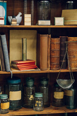 Vintage books and jars on a shelf in an apothecary.