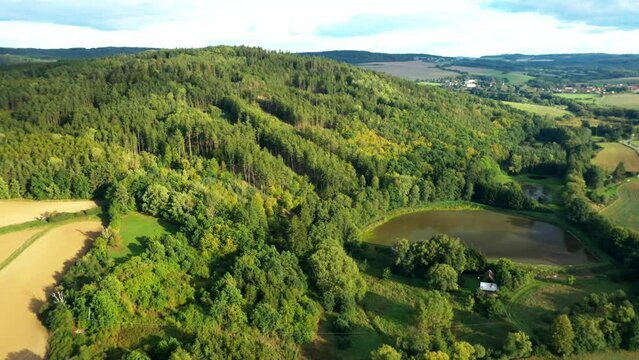 A pond in the middle of the woods. Drone flight over rural landscape. The Bohemian forest Hills on the Czech countryside. Central Europe.
