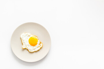 Fast breakfast with one fried egg on plate, top view