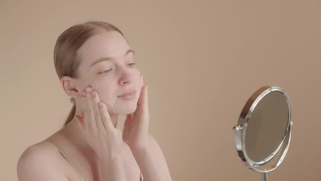 Young woman 20s uses a facial cleansing foam to remove makeup