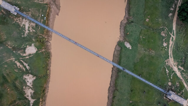 Aerial Top-down View of River and a Suspension Bridge in Rural Nepal During Monsoon Season