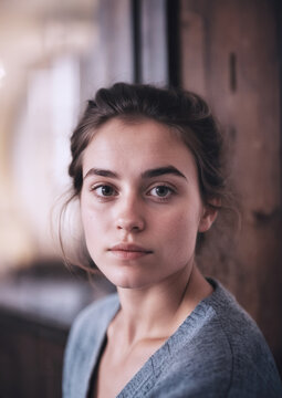 ritratto primo piano di giovane donna dallo sguardo serio, luce ambiente naturale capelli raccolti