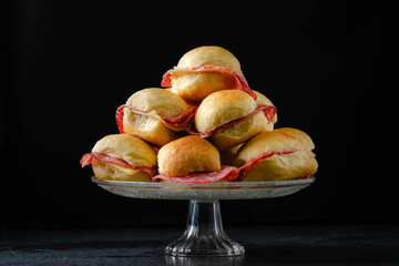 Butter figacitas, small salami and cheese sandwich. Close-up, glass plate, on marble, granite table, black background