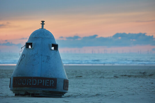 Buoy on a north sea beach in the Netherlands at sunset