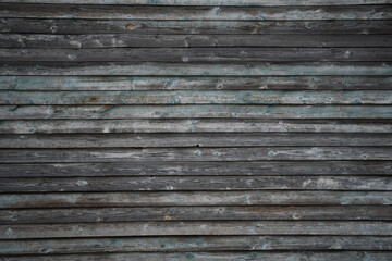 Old wooden wall made of horizontally stacked boards with peeling blue paint