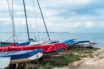 Shallow focus on moored and covered boats on the beach in Whitstable with the Isle of Sheppey on the horizon. - 652979913