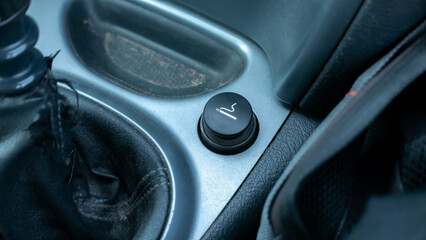 Electric cigarette lighter in an old worn dusty dirty car interior, car inside detail shot,...
