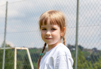 Happy school age child young kid in white shirt smiling outdoors portrait, face closeup, copy space, blurred background, one person. Cheerful European Caucasian girl. Summer vacations, sunny weather