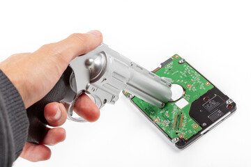 Man, hand holding a HDD disk drive at gunpoint, silver revolver aiming at private user data on a drive. Ransomware malware, phishing, hacking, files theft, permanent deletion simple abstract concept