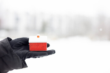 Woman holding a red model house in the snow.