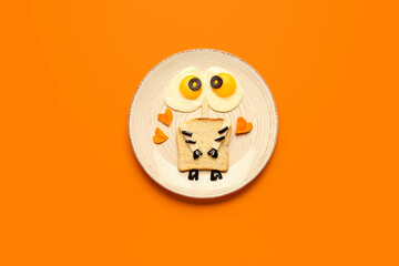 Plate with funny children's breakfast on orange background