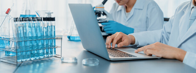 Dedicated group of scientist conduct chemical experiments and research in medical lab as groundbreaking developing for new vaccine drug or antibiotic and studying test result on laptop. Neoteric - obrazy, fototapety, plakaty