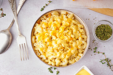 Bowl of tasty Italian pasta with Cheddar cheese on light background