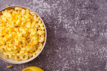Bowl of tasty Italian pasta with Cheddar cheese on grunge background