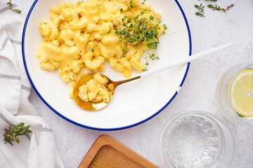 Bowl of tasty Italian pasta with Cheddar cheese on light background