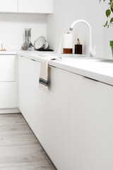 White counters with sink and utensils in light kitchen