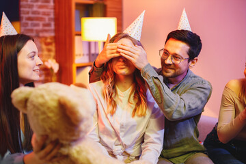 Friends sitting on a sofa in a cozy room and celebrating birthday