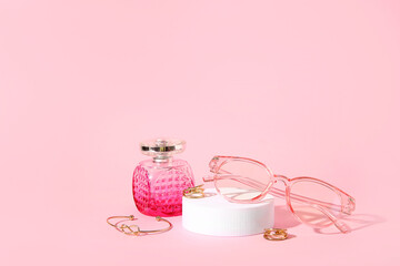 Podium with stylish sunglasses and perfume on pink background