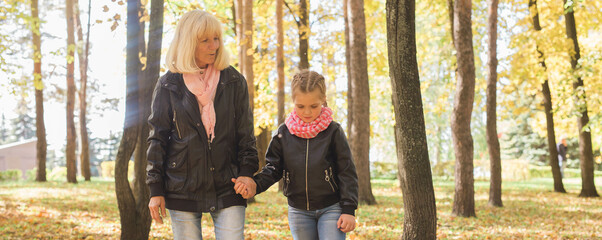 Grandmother with granddaughter in autumn park banner copy space. Generation and family concept.