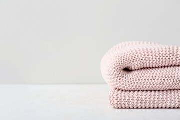 New knitted folded blanket on table near light wall