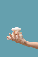 Hand with soap bars on blue background